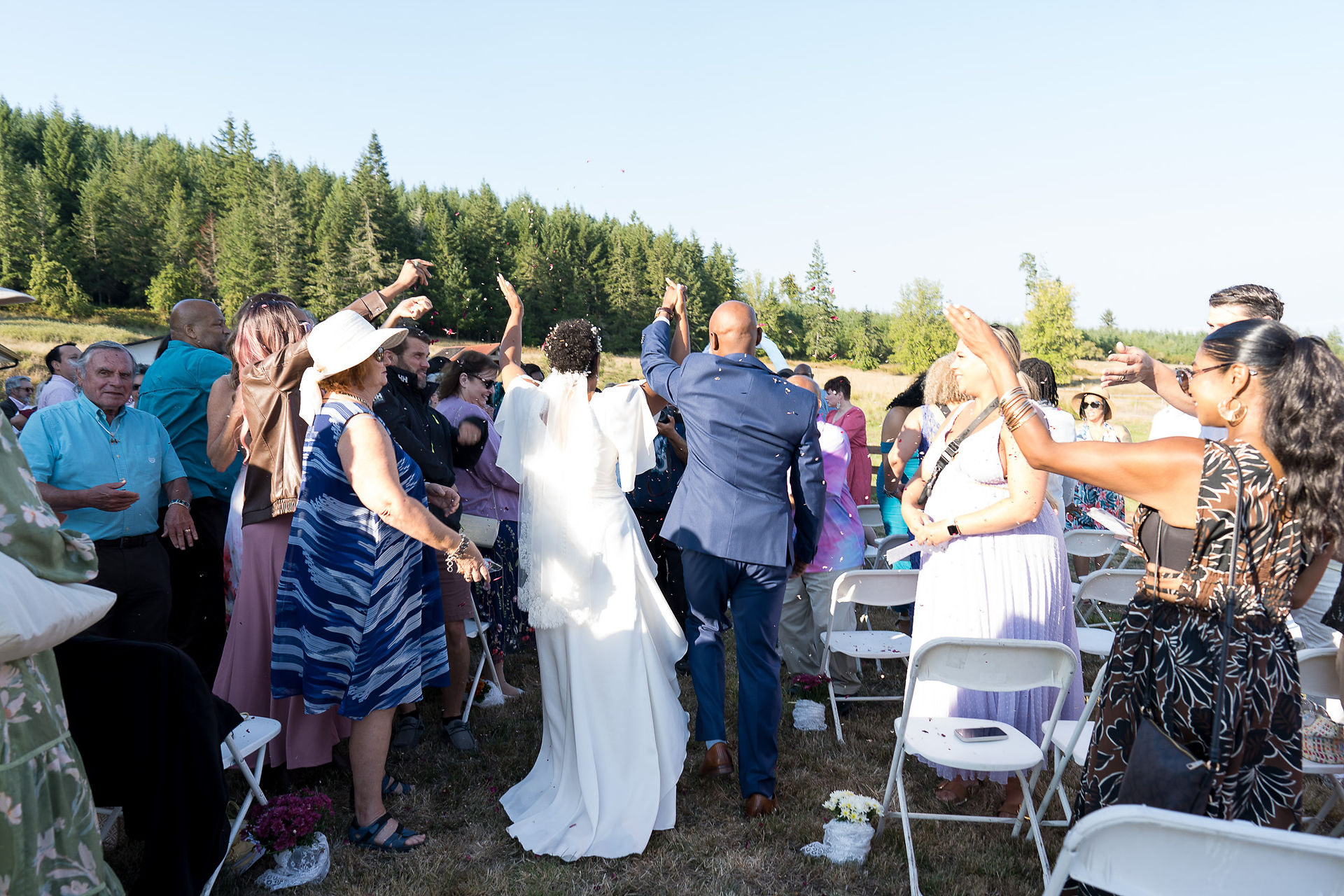 Newlywed couple exits through cheering guests at intimate outdoor farm wedding.