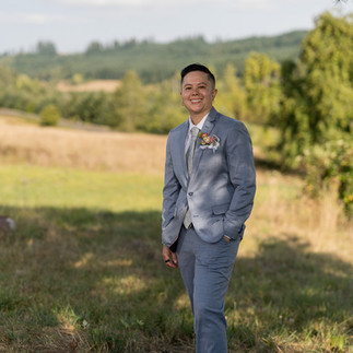 Groom in blue suit smiles at an intimate farm wedding.