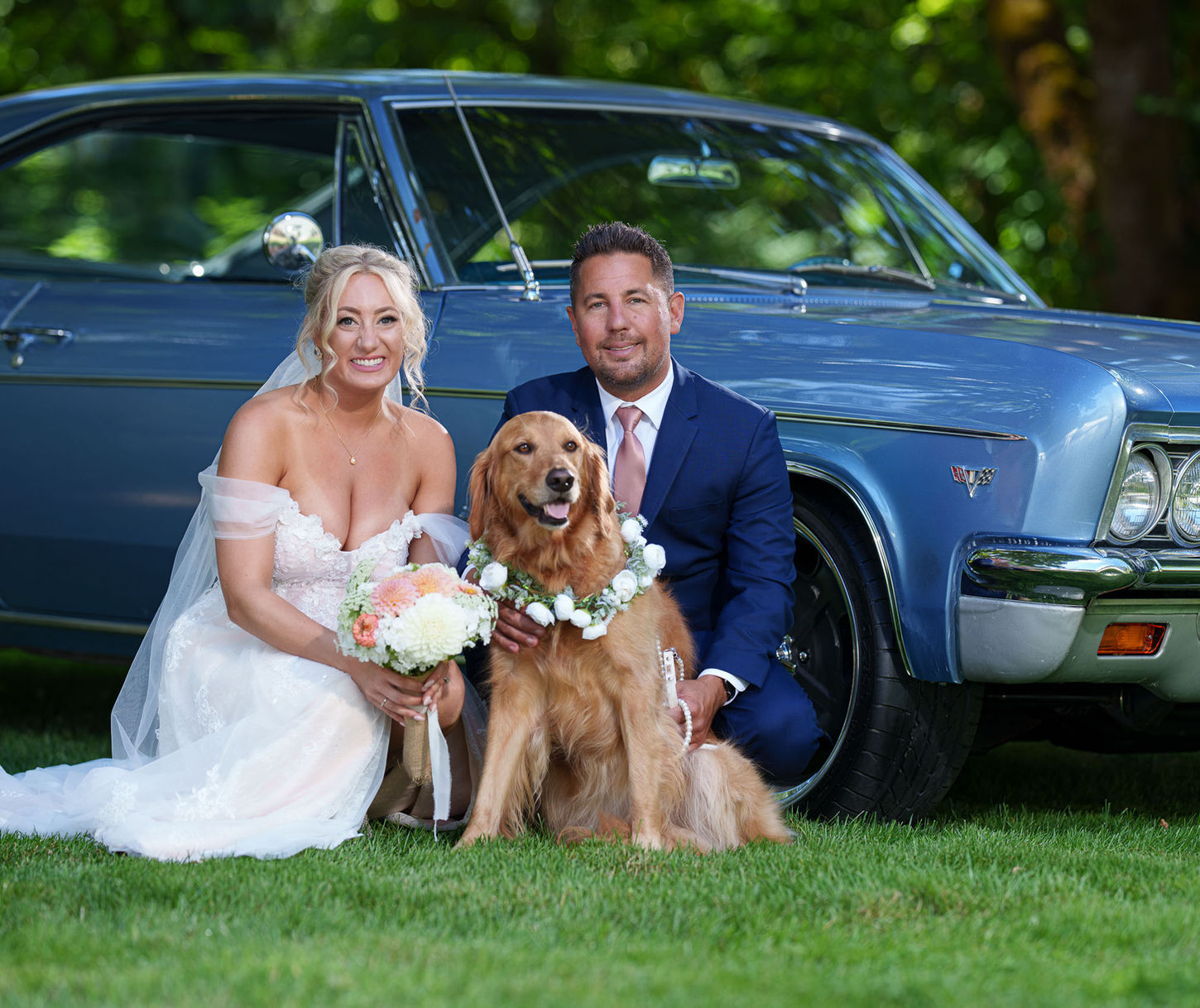 Newlywed couple, golden retriever in wreath, blue vintage car.