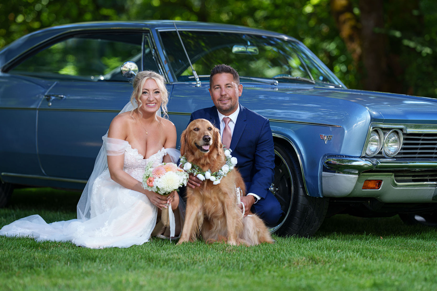 Newlywed couple, golden retriever in wreath, blue vintage car.