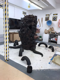 large monolith covered in faces with vines coming out the ground