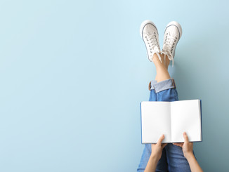 legs of woman sitting with blank notebook open in lap
