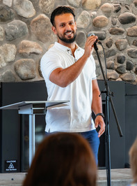 Smiling man in white shirt speaking into microphone