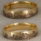 Gold ring with engraved mountain design, resting on a textured fabric. Ring appears polished and detailed, creating an elegant and rustic look.