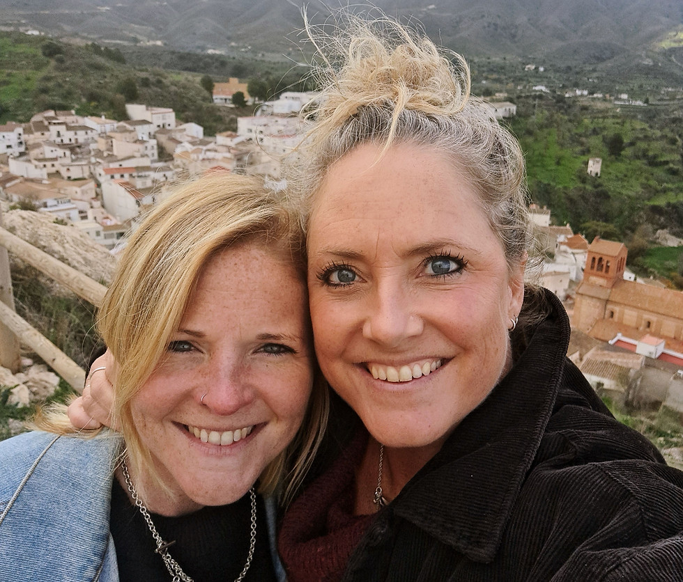 Niamh and Eppie co-founders of Rock House Marketing, smiling together at a scenic hilltop viewpoint overlooking a traditional Spanish white village and mountains.