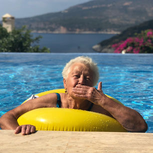 An elderly lady enjoying some time in an infinity pool.