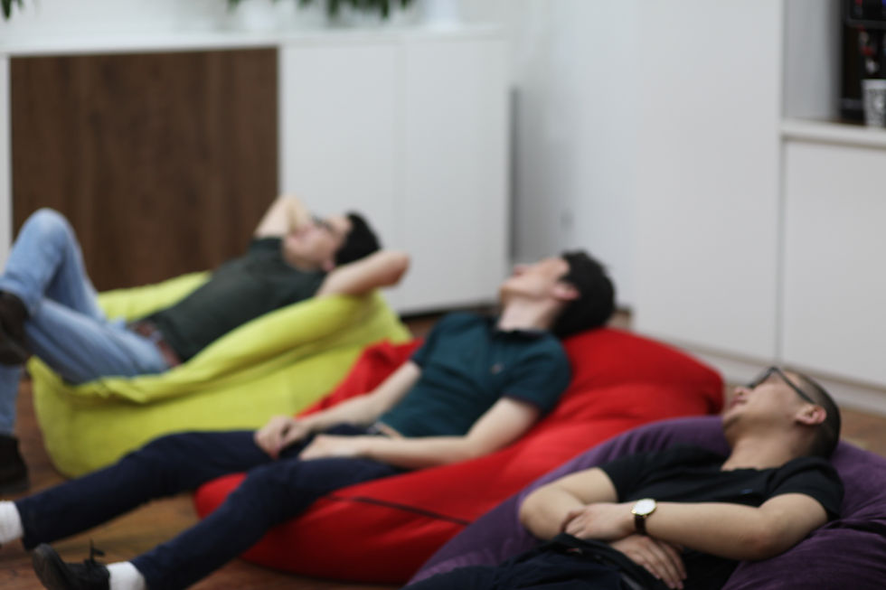 Three people lie back trying to rest on coloured bean bags.
