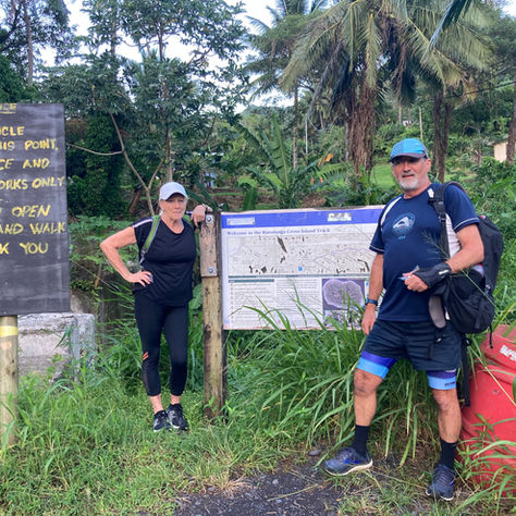 Margaret and Stephen leaning on a sign about the Rarotonga Cross Island Walk