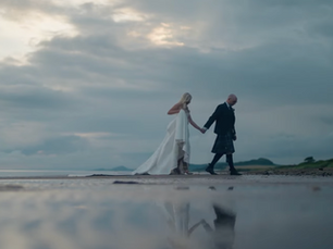 Bride and groom walking along a Scottish beach at dusk, reflected in shallow water, filmed by CW Wedding Films