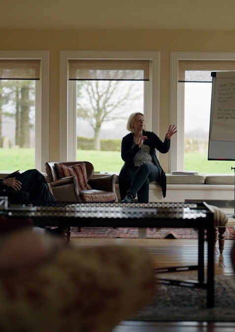 Group workshop session in a cozy, well-lit living room with large windows overlooking the green landscape of Loch Lommand.