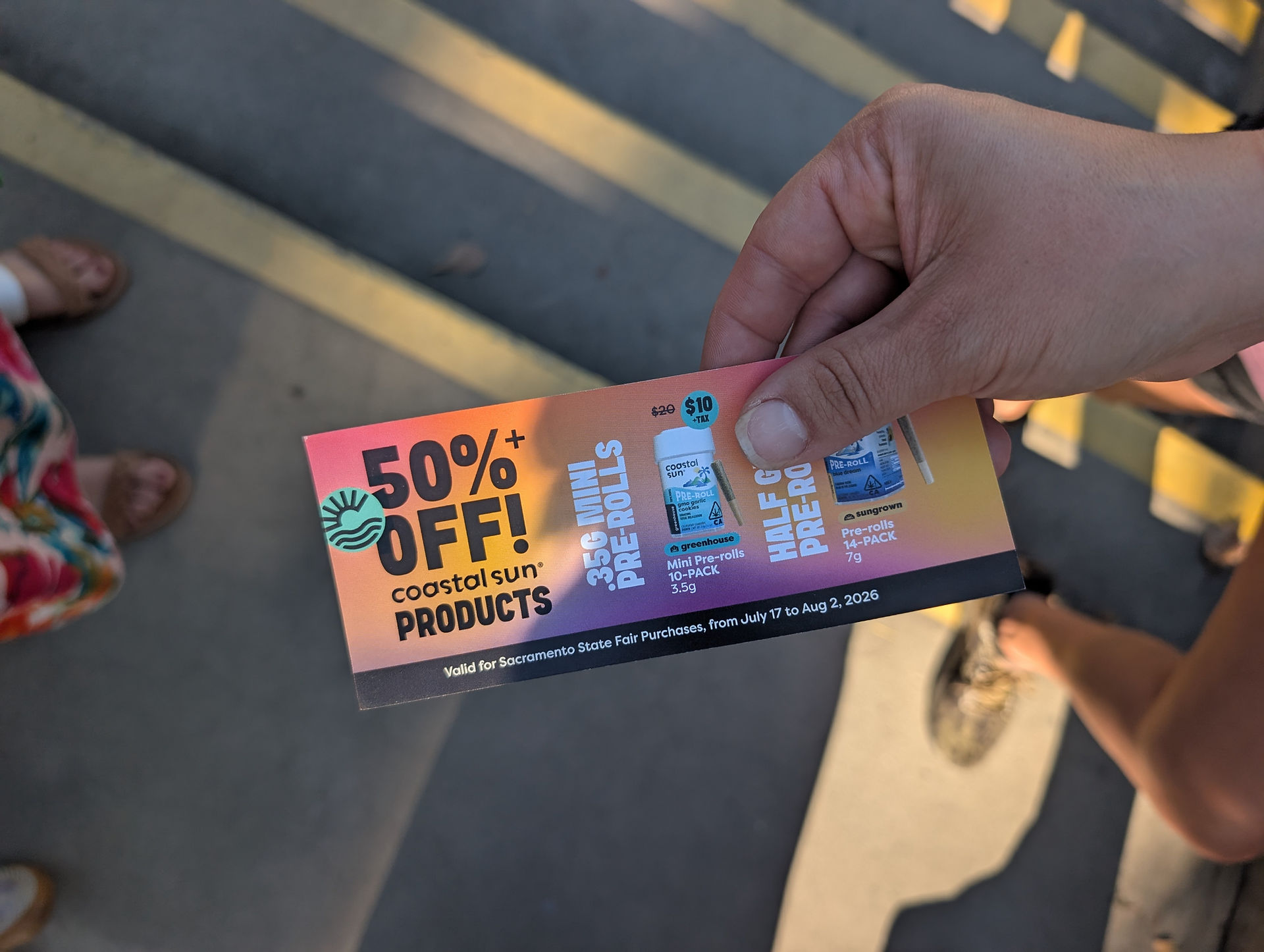 someone's hand with a voucher for 50 percent off Coastal Sun products