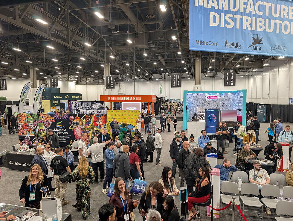 People at MJBizCon bustle around the trade show with colorful booths and banners. A large blue banner reads "Manufacturer Distributors." Attendees chat amiably.