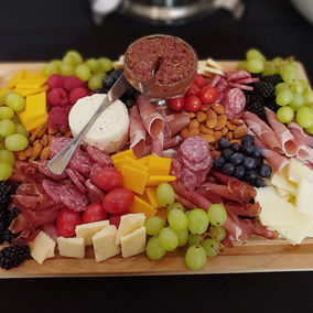 Charcuterie board with grapes, assorted meats and cheeses, almonds, cherry tomatoes and raspberries.