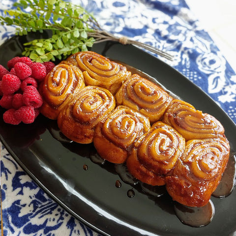 Caramel rolls on a platter with raspberries