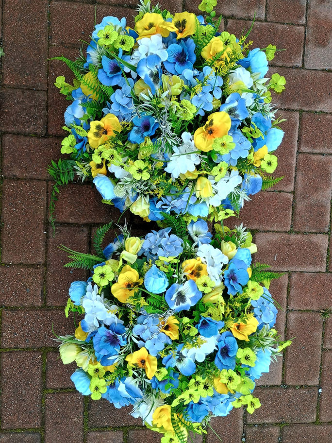 Two vibrant blue and yellow flowers are positioned on a brick walkway, creating a charming outdoor display.