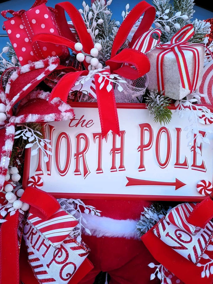 Festive wreath says the North Pole with gifts and red decorations.