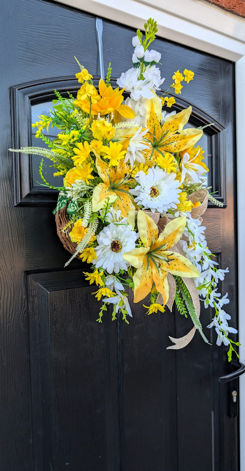 Thumbnail: Yellow flower arrangement hanging on black door; sunflower wall and fence planter.