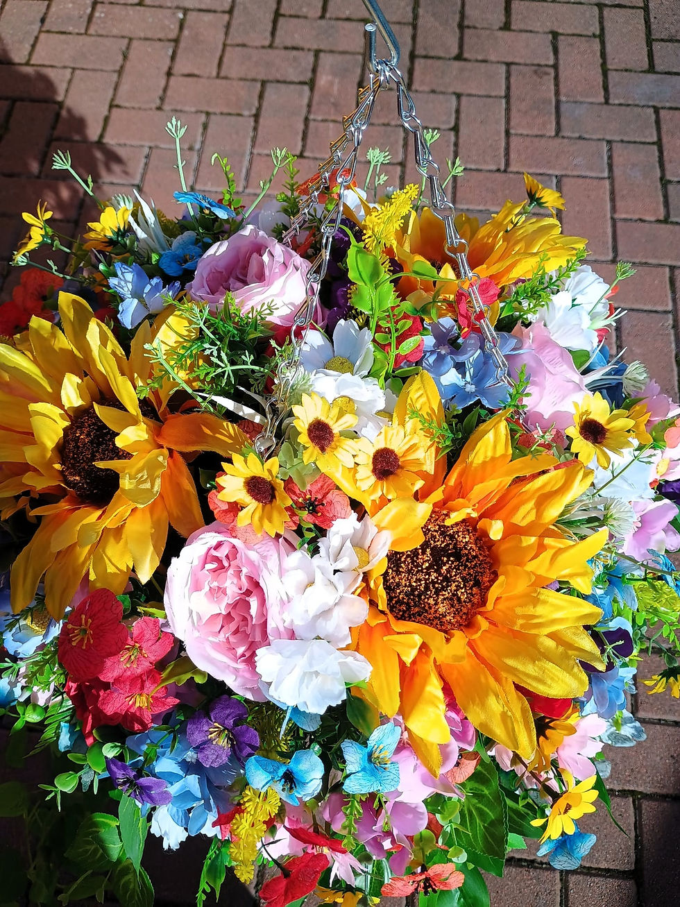 Thumbnail: A beautifully arranged basket filled with sunflowers, daisies, hydrangeas, and roses, accented with complementary foliage