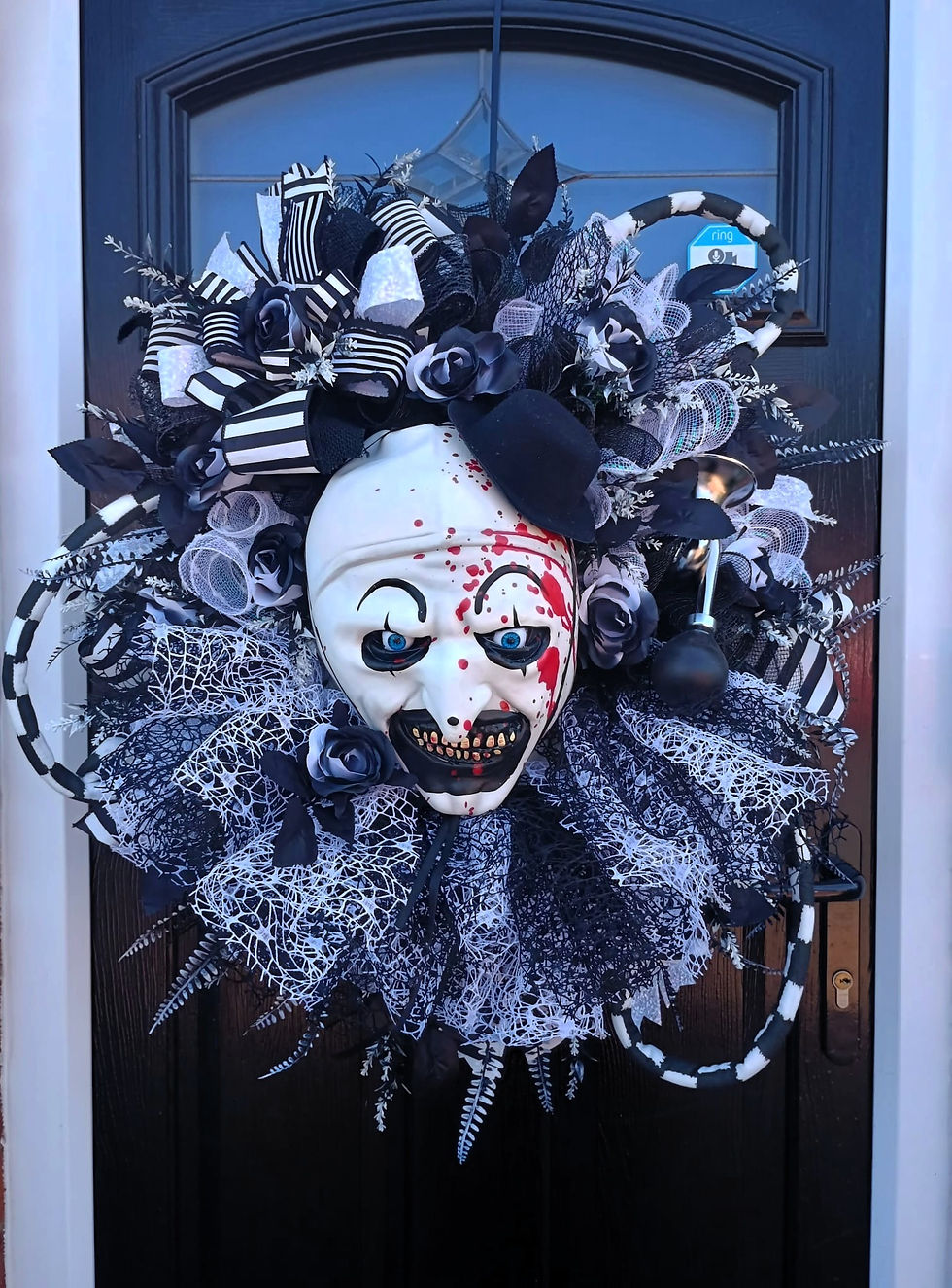 Creepy clown wreath with scary face and black and white decoration detail.