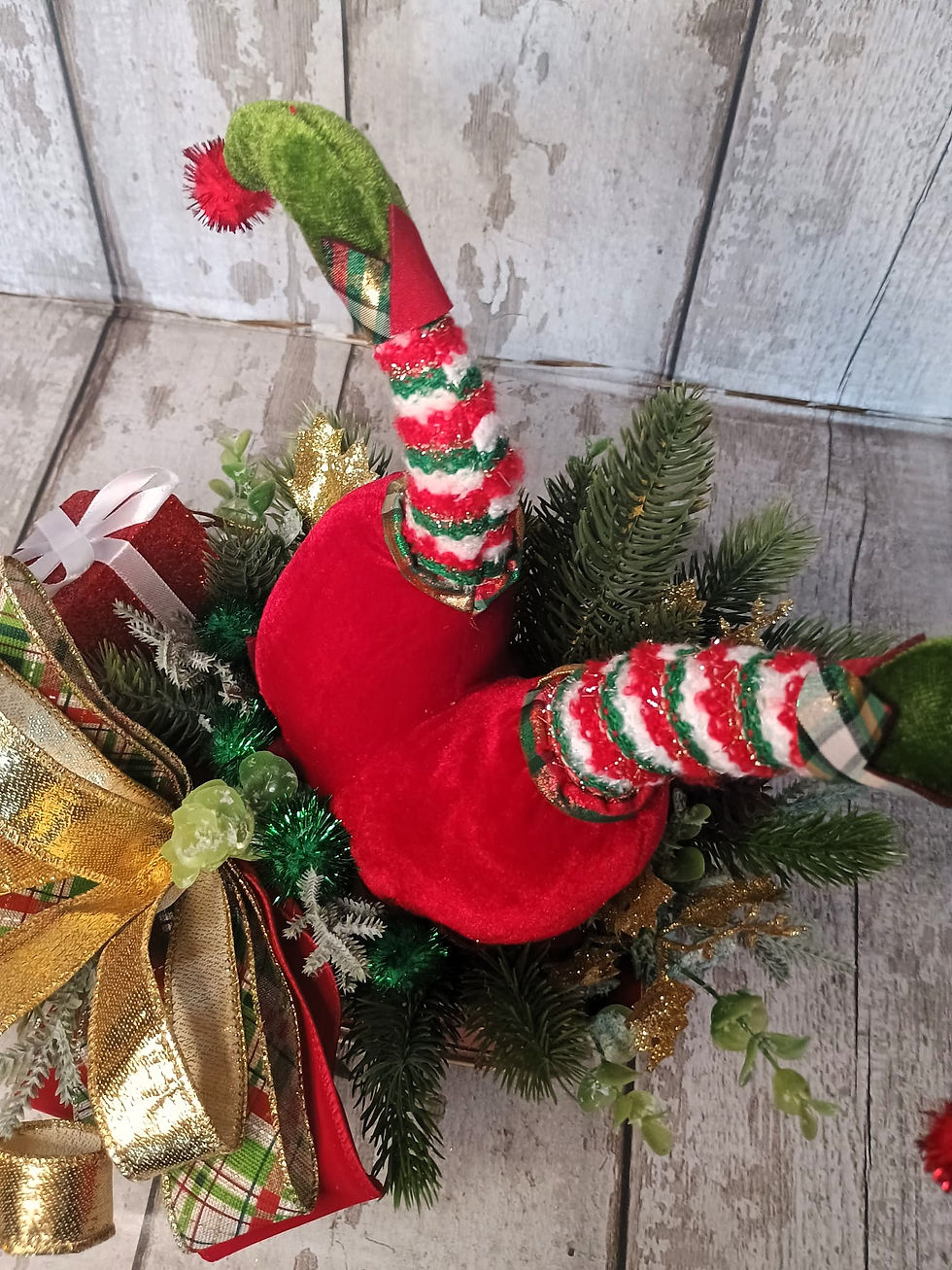 Thumbnail: Christmas elf legs emerging from festive decorations, gift box and bow.