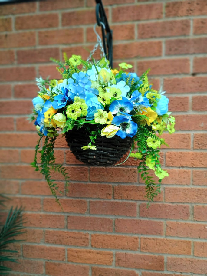 Two vibrant blue and yellow flowers are positioned on a brick walkway, creating a charming outdoor display.