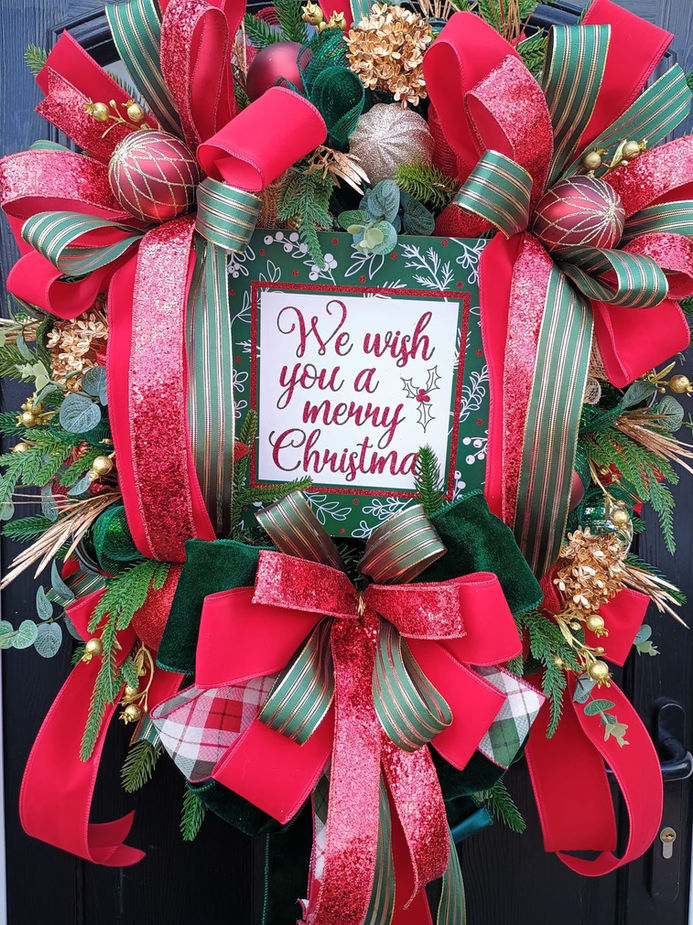 Festive Christmas wreath with red ribbons and message: We wish you a merry Christmas.