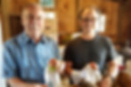 Two men holding apples in a barn with boxes of apples