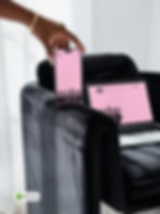 Hand with gold bracelet holding iPhone next to laptop on black velvet chair showing multi-device responsive design