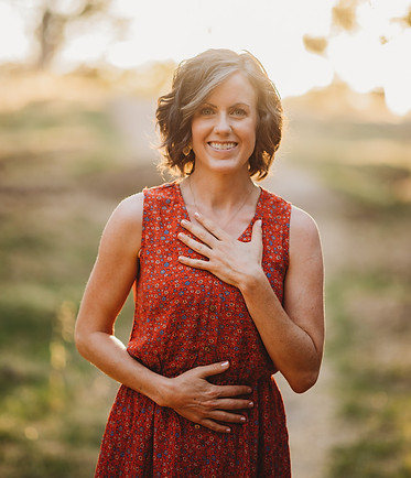 Joyful Hearts Healing Owner, Emily Green, smiling toward camera with hands on heart and stomach