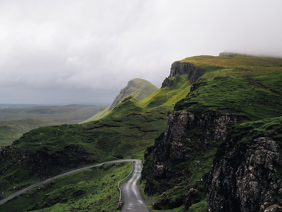 A winding road among cliffs and a foggy sky