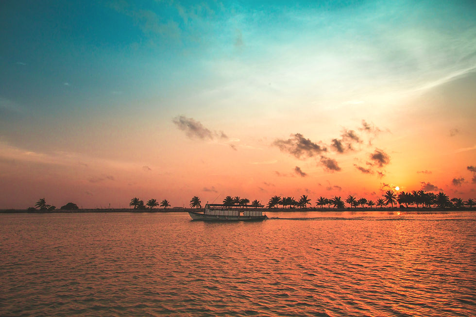 Boat on water at sunset, sky transitioning from orange to blue, silhouetted palm trees in the distance. Calm and serene mood.