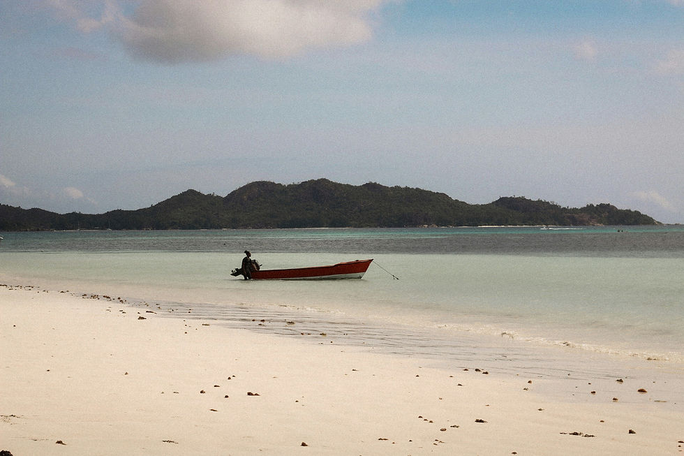 Quiet Seychelles beach with a red boat and calm turquoise water