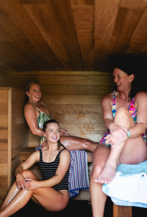 Three guests enjoying a community sauna session inside Revivo Sauna's handcrafted wood-fired outdoor sauna.