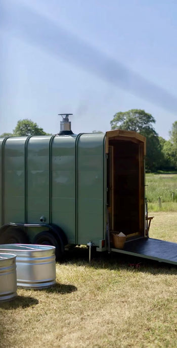 Revivo Sauna's handcrafted wood-fired outdoor sauna and cold plunge tubs at a community wellness pop-up in the Cambridgeshire countryside.