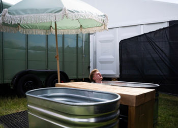 Guest relaxing in a cold plunge beside Revivo Sauna's wood-fired outdoor sauna during the British Grand Prix weekend at Silverstone.