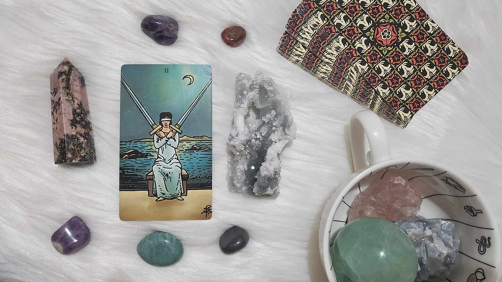 The Two of Swords tarot card surrounded by crystals.