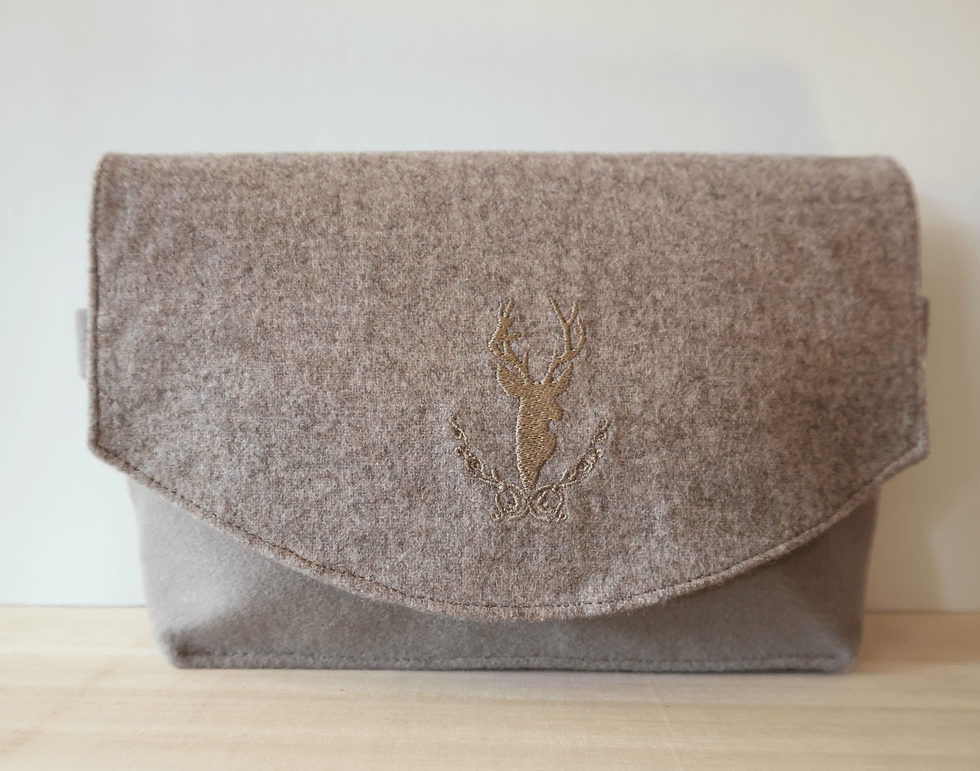 Miniaturbild: kleine Trachtentasche in Beige-Tönen mit Hirschmotiv auf Holztisch