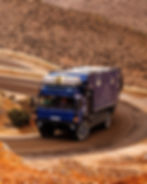 blue MAN HX60 overland expedition vehicle on a winding desert road