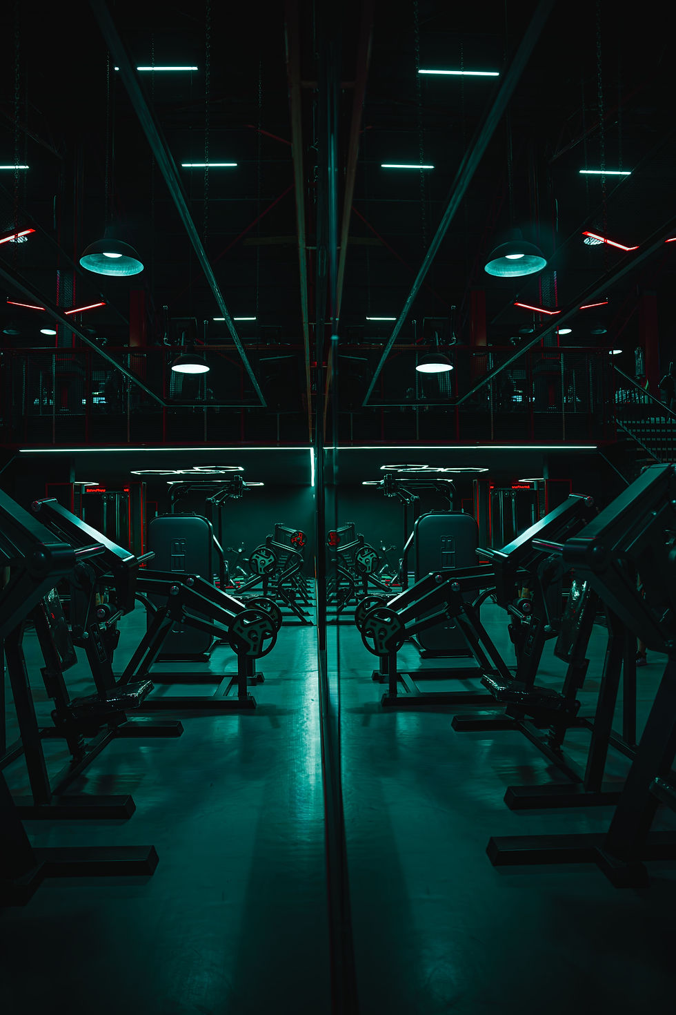 Empty neon-lit gym with mirrored rows of strength machines and teal lighting, creating a dark futuristic mood
