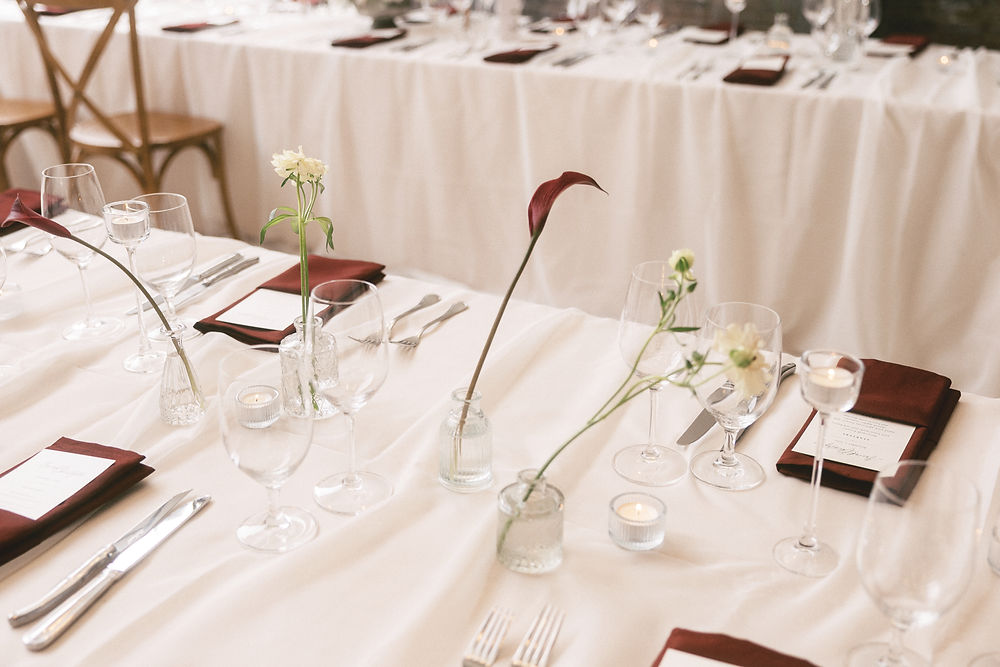 wedding table setting with bud vases and burgundy napkins
