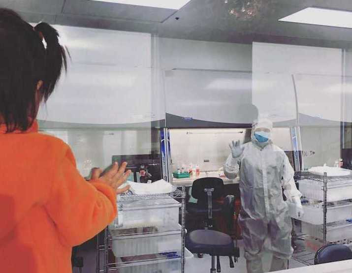 Manufacturing technician, Raul, waves to a curious little Hope Banker from inside the laboratory.