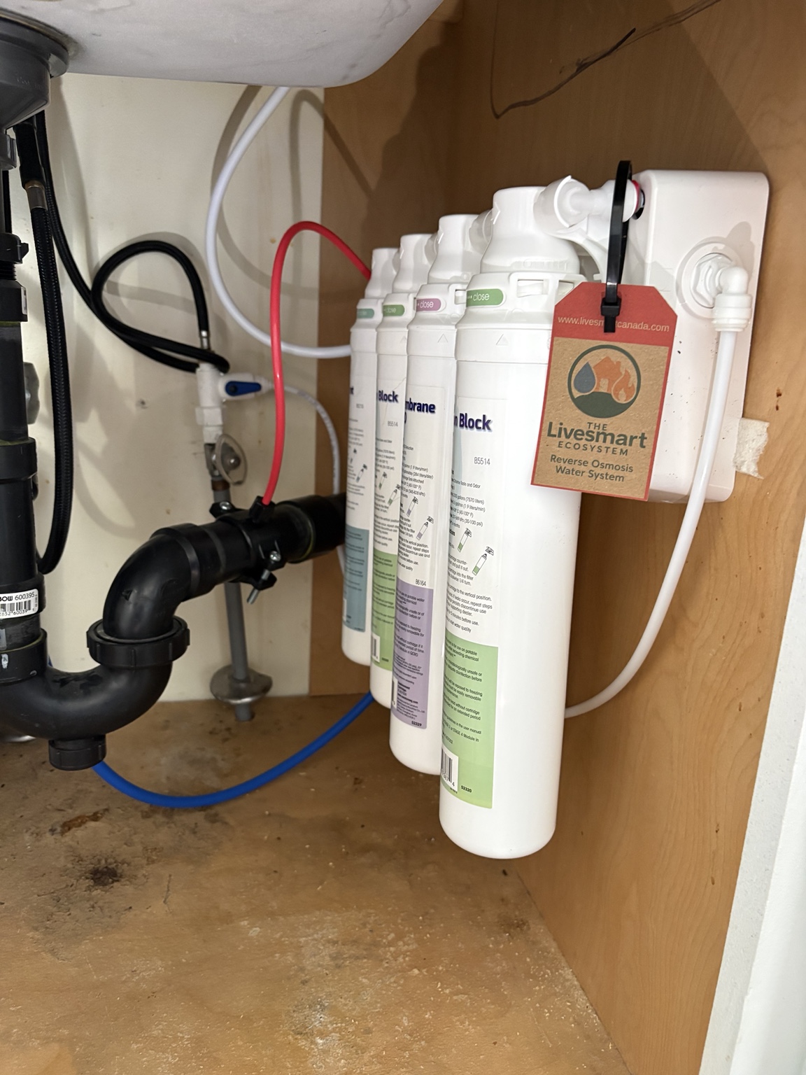 Drinking-water filter cartridges and a LiveSmart tag inside a wooden kitchen cabinet