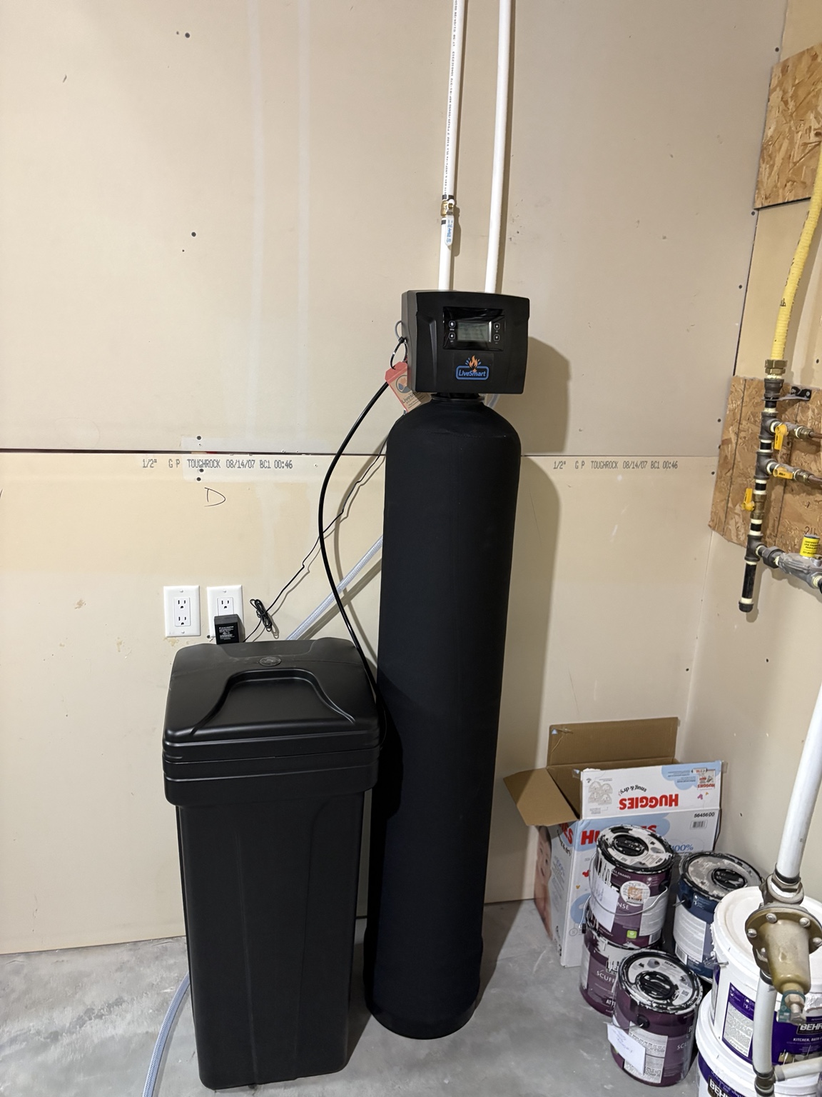 Black LiveSmart softener and separate brine tank installed in an Oliver utility room