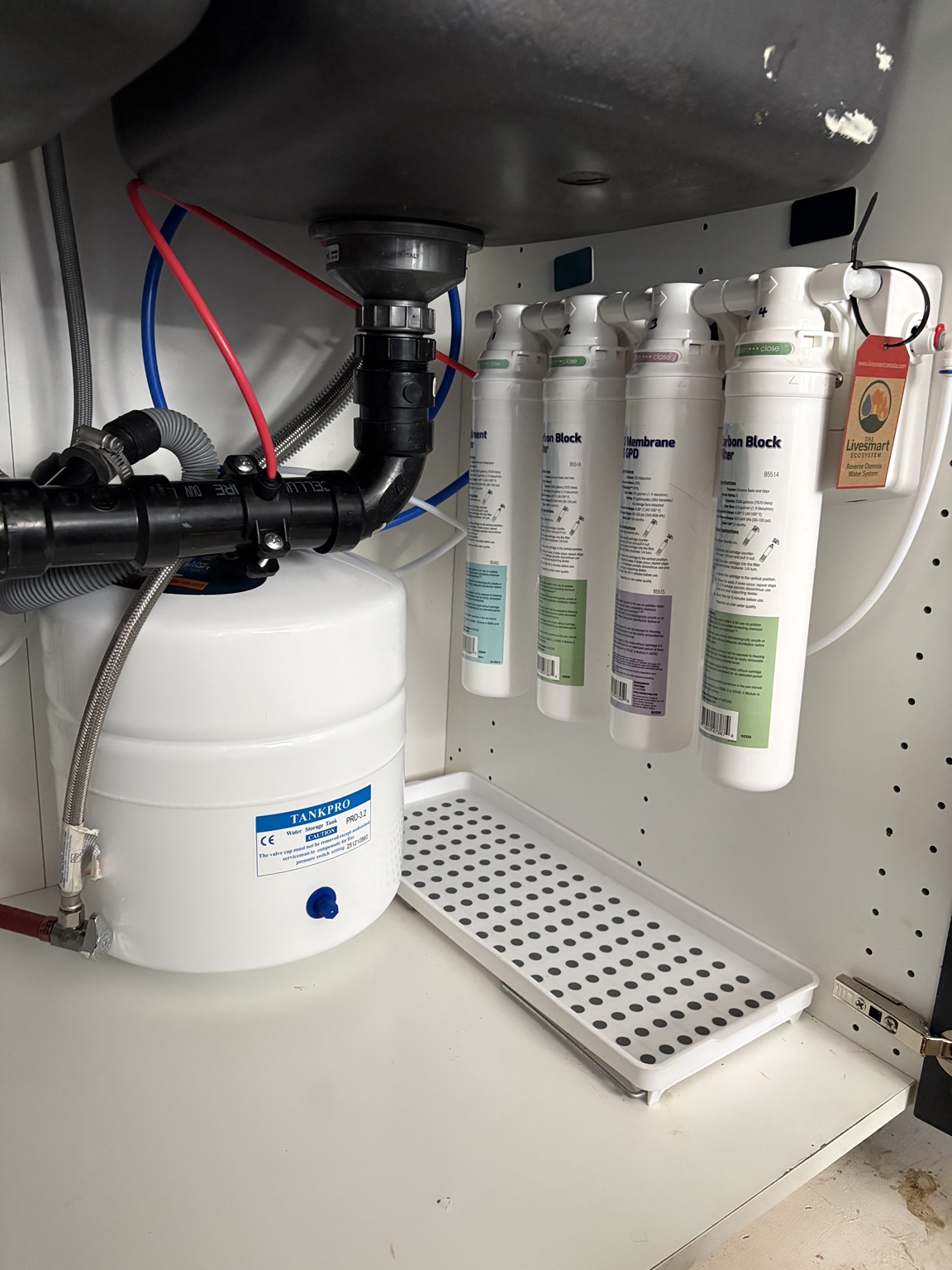 Drinking-water filters and a white storage tank under a kitchen sink