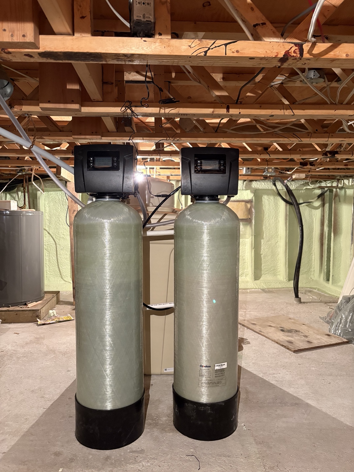 Two custom water-treatment tanks installed beneath exposed floor joists in a Clearwater Lake crawlspace