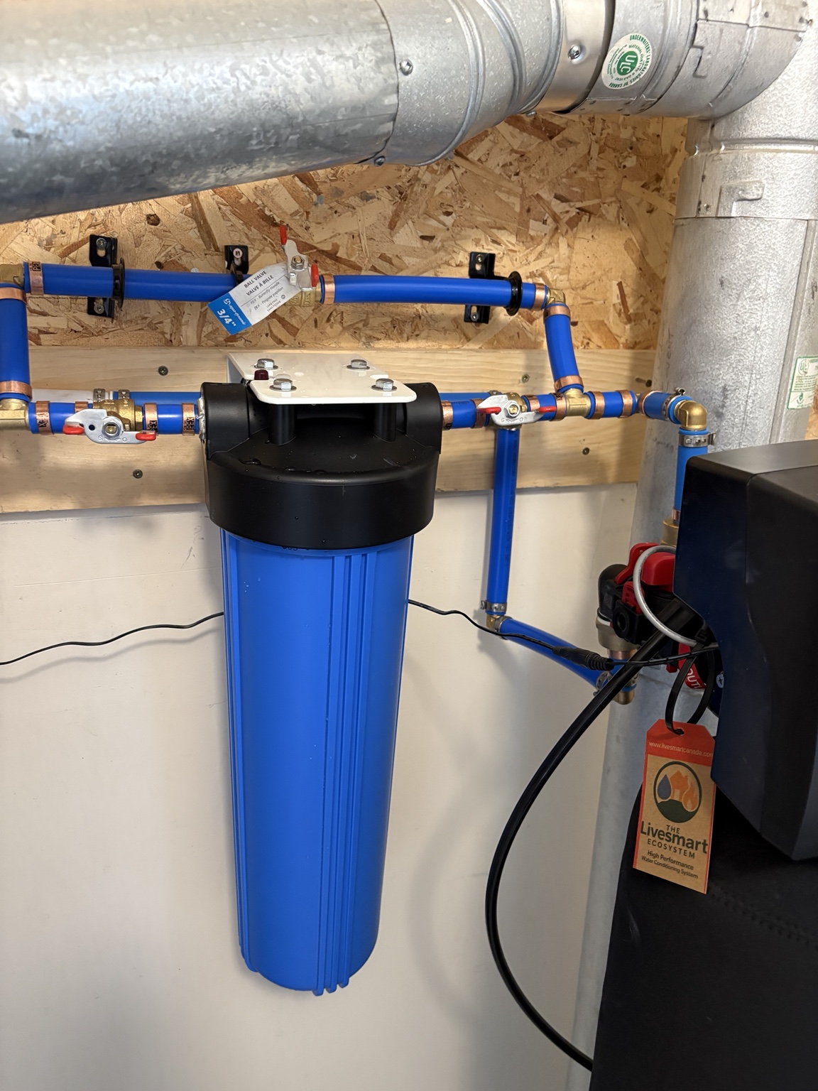 Blue prefilter housing and blue plumbing beside a black LiveSmart system