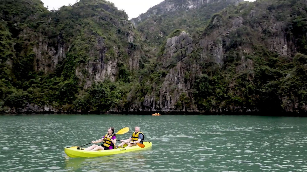 Travellers kayaking among limestone cliffs in Hạ Long Bay, Vietnam.