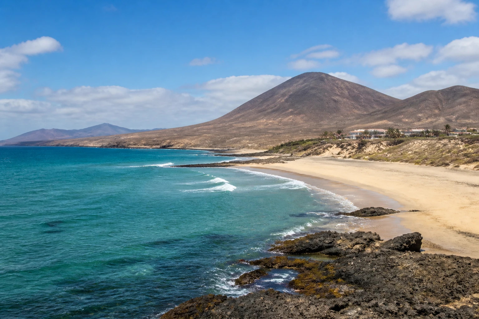 Representative island destination view: Fuerteventura, Spain; coastline and regional vegetation, not an exact landmark photograph.