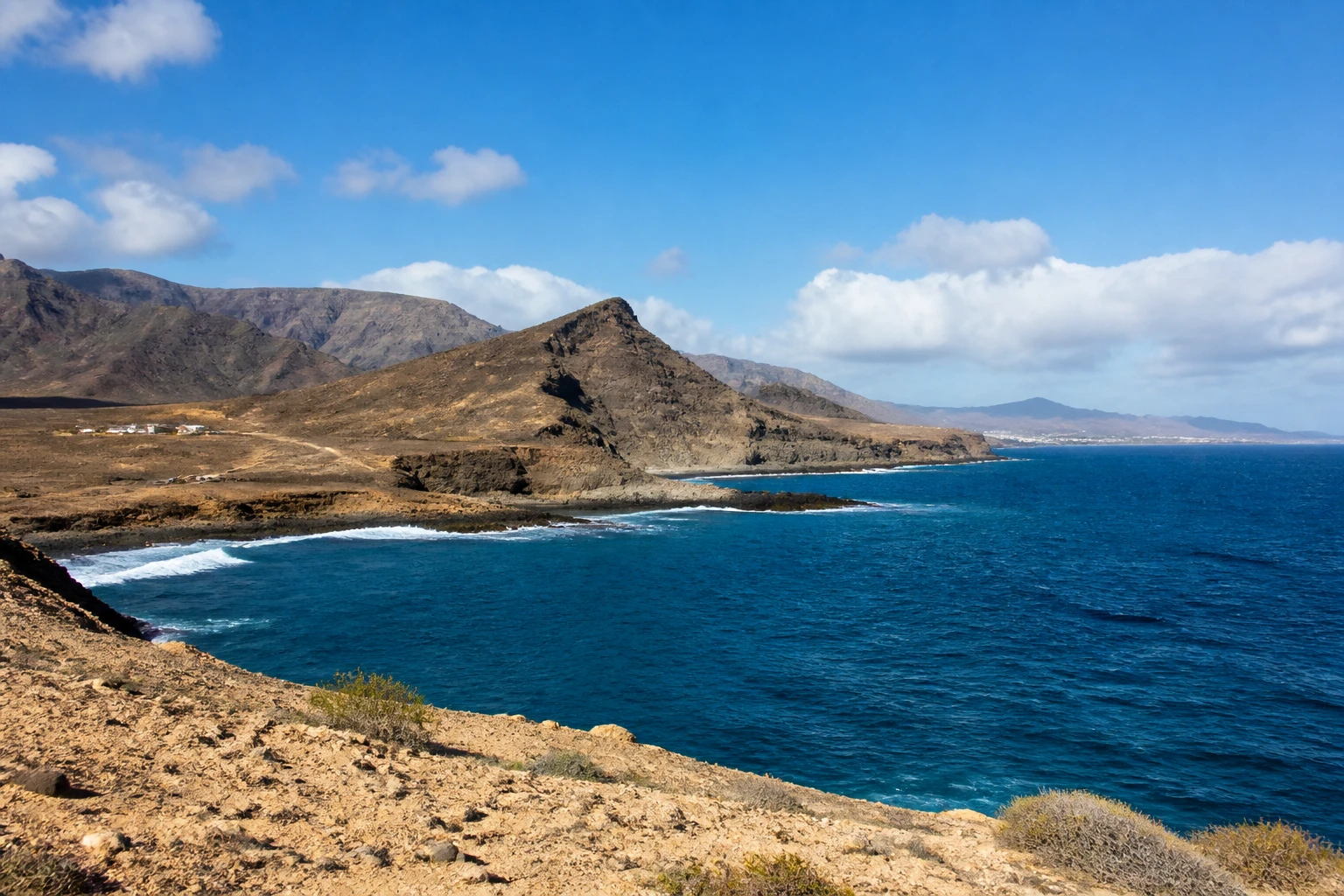 Representative island destination view: Gran Canaria, Spain; coastline and regional vegetation, not an exact landmark photograph.