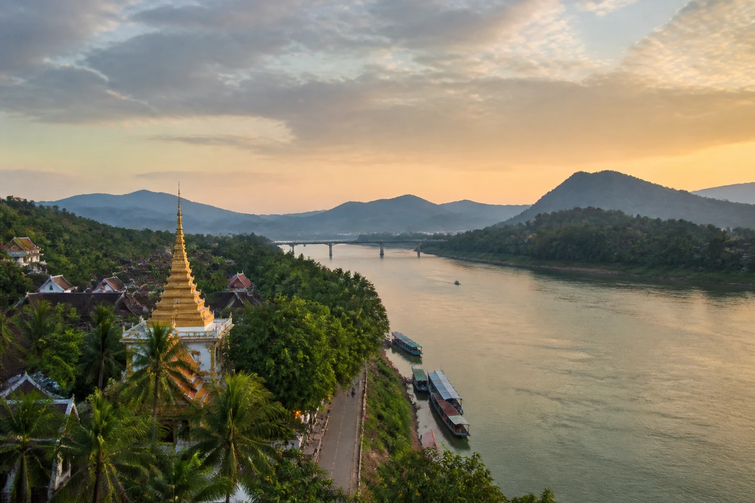 Representative river destination view: Luang Prabang, Laos; inland water, regional terrain, and vegetation, not an exact landmark photograph.